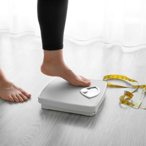 someone weighing themselves on a scale to see the progess of their personal training for weight loss